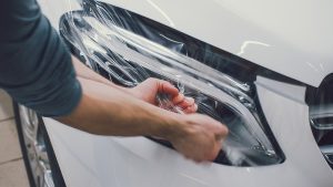 Technician applying paint protection film to a vehicle’s hood at Spotless Car Spa in Burlington